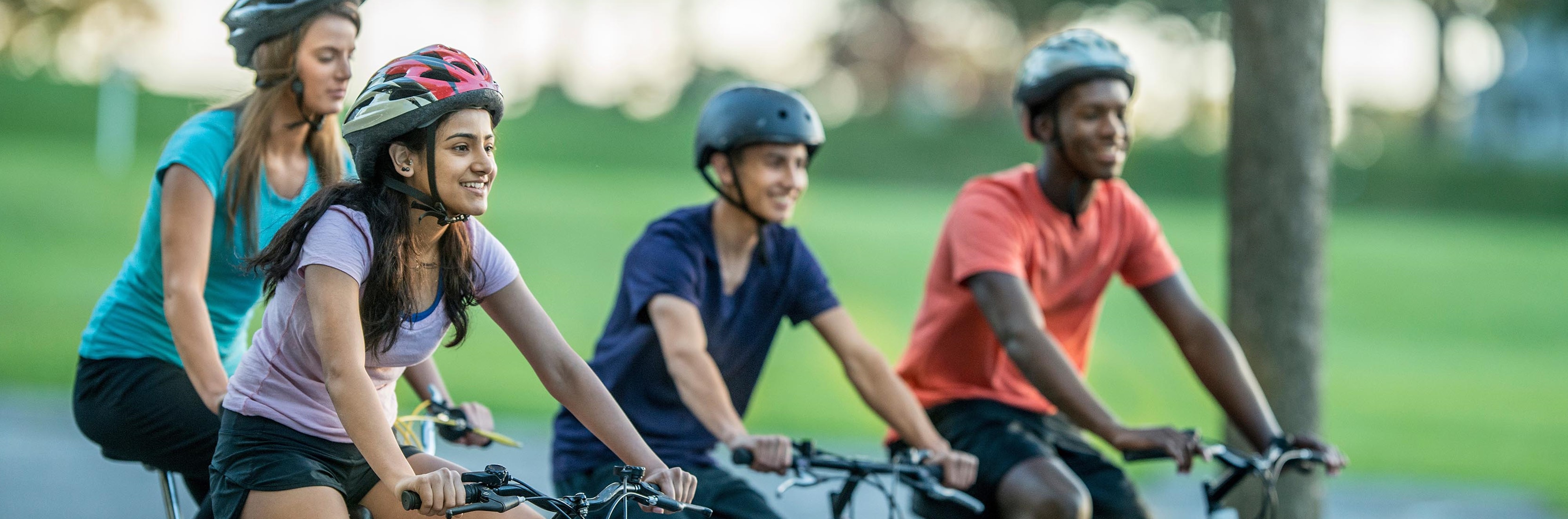 A group of teenagers smiling and riding bikes