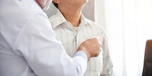 Doctor listening to older patient’s chest with stethoscope.